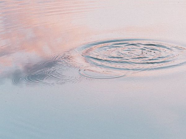 Calm water surface reflecting the sky, symbolizing flow.